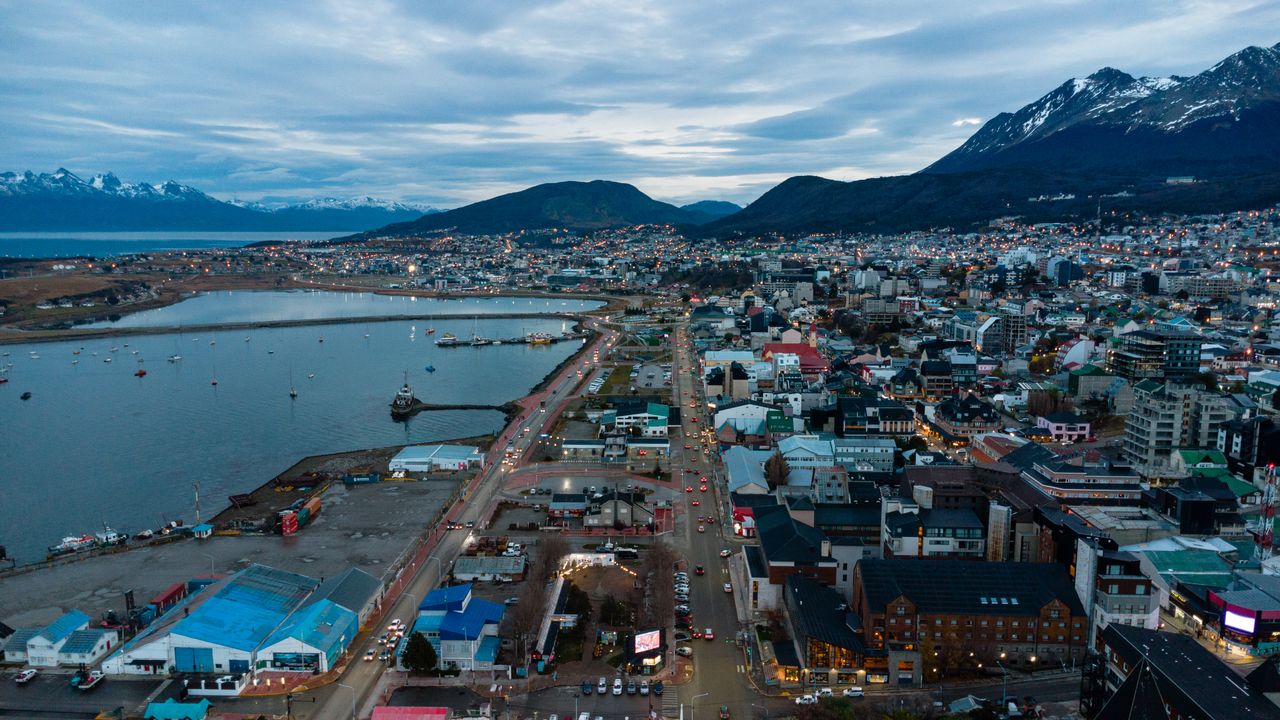 Twilight aerial view of Ushuaia, Argentina, surrounded by mountains and sea.